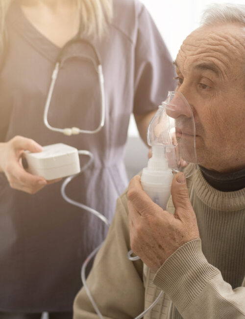 Nurse provides breathing treatment for elder patient.