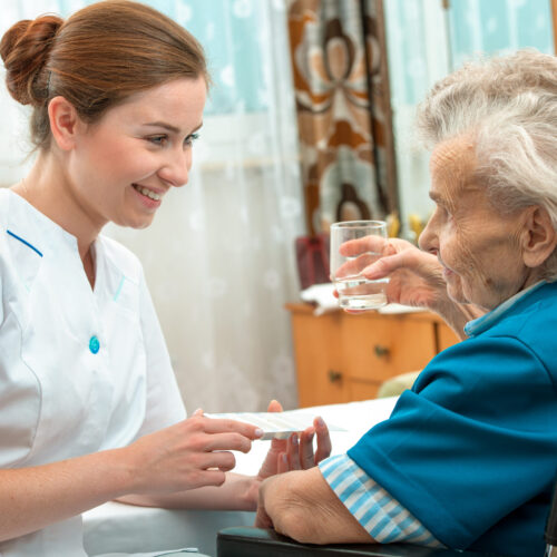 female nurse giving senior woman medical pills